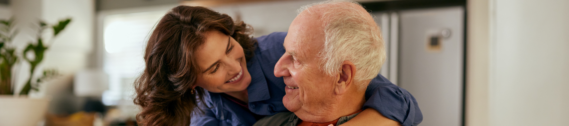 Lovely adult daughter embracing senior father from behind